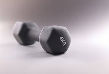 Black sports dumbbell for bodybuilding on gray background closeup. Sale of sports accessories concept