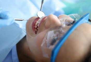 Dentist examining oral cavity of woman patient in clinic using tools closeup. Annual dental checkups concept