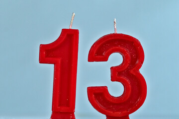close up on red number thirteenth birthday candle on a white background.
