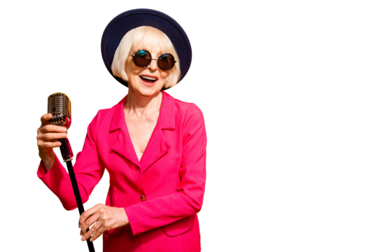 Portrait of happy old woman holding a microphone stand and singing isolated on vivid yellow background with copy space for text