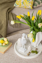 Interior design of easter dining room with colorful easter eggs, easter bunny sculptures, vase with tulips, white trace, decorations and personal accessories. Home decor Template