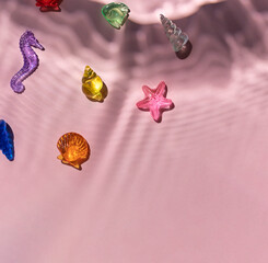 Marine transparent colorful figurines or kid's toys with under water texture light shadows on the pink background. Summer sea vacation concept composition. Copy space