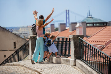 Happy young family on trip lift hands up in Lisbon, Portugal - 755577077