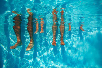 People legs dangling in pool, view from underwater on sunny day - 755577454