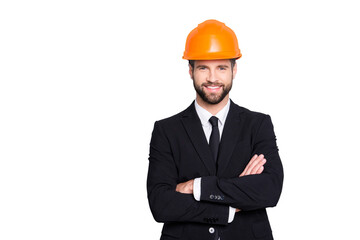 Portrait of attractive young stylish investor with stubble in orange hard hat and black tux, tuxedo with tie, looking at camera, isolated on grey background, having his arms crossed