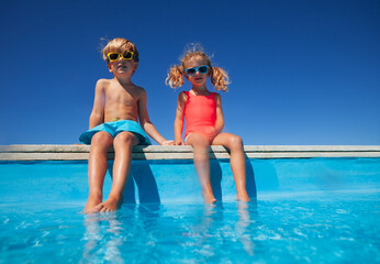 Siblings enjoying sunny day together dip their feet in pool - 755577817