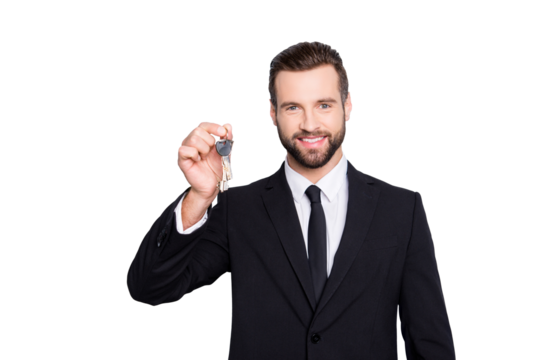 Portrait of attractive stylish real estate with bristle, stubble in black tux, tuxedo and modern hairstyle having key from new house in hand isolated on grey background