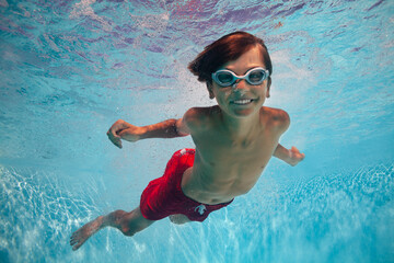 Underwater shot of a cheerful boy smiling in camera while swim - 755578069