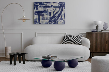 Cozy composition of living room interior with mock up poster frame, glass coffee table, stylish white sofa, pillow, wooden sideboard, sculpture and personal accessories. Home decor. Template.