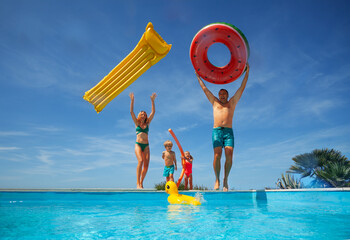 Kids and parents play with pool toys toss in the air, jumping - 755580623