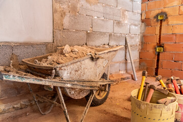 Buckets full of tools and a wheelbarrow full of pieces of plaster - 755583283