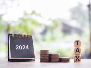 2024 desk calendar, Wooden block with word TAX on stack of coins. The concept of saving money for...