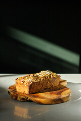 Homemade oat and nuts bread on a cutting board. Black background with shadows. Copy Space.