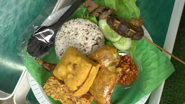 Uduk rice, fried chicken, chicken gizzard liver, tofu, tempeh, cucumber, chili sauce and lalap, into one plate