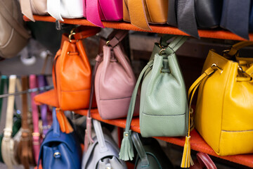 Close up of different leather bags on market. Modern colorful bags for sale. Womanly accessories