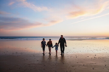 Fototapeta na wymiar Portrait silhouettes of three children and dad happy kids with father on beach at sunset. happy family, Man, two school boys and one little preschool girl. Siblings having fun together. Bonding