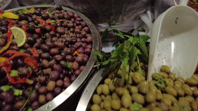 different types of Italian or Spanish fresh and marinated olives with spices, herbs and olive oil at the local market