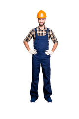 Full size fullbody portrait of joyful attractive repairer in shirt and overall, holding his arms on waist, looking at camera, isolated on grey background