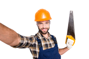 Portrait of handsome cheerful master in overall, shirt, hardhat, uniform shooting selfie on front camera, showing saw in arm, having leisure fun, isolated on grey background