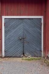 Black door with white frames on a old red painted wooden building.
