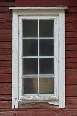 Fototapeta na wymiar White framed window on a old red painted wooden building.
