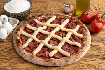 Calabrian sausage and Catupiry cream cheese style pizza over stone background with tomatoes, flour...