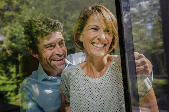 gl&uuml;ckliches Paar schaut aus dem Fenster einer neuen Immobilie, Bayern, Deutschland