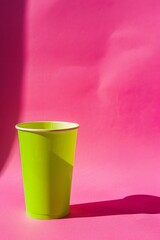 A neon green beverage cup on a hot pink background