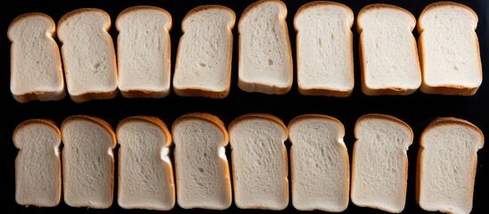 Several white bread slices are neatly arranged on a table, showcasing their different sizes and shapes. The bread sits on a black surface, creating a stark contrast.
