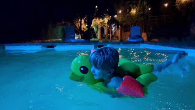 Child with inflatable duck enjoys night swim during pool party