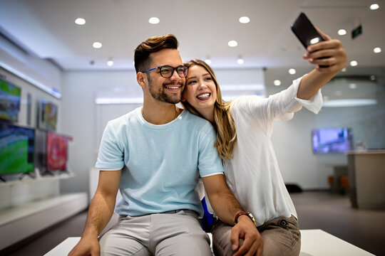 Smiling couple have fun using smartphone, watch video on cellphone make self-portrait picture