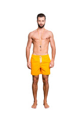 Full size body portrait of fit sportive lifeguard with stubble in yellow shorts isolated over grey background, looking at camera