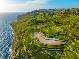Aerial drone view of green fields, cliffs and hills of Maltese island, nature landscape, blue sky. Mediterranean sea