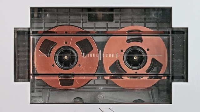 Close-up tape recorder audio cassette analog rotate golden disk and plays music macro. Analog tape recorder plays  audio cassette spins plays music close up slide top front. Retro tape reels rotate