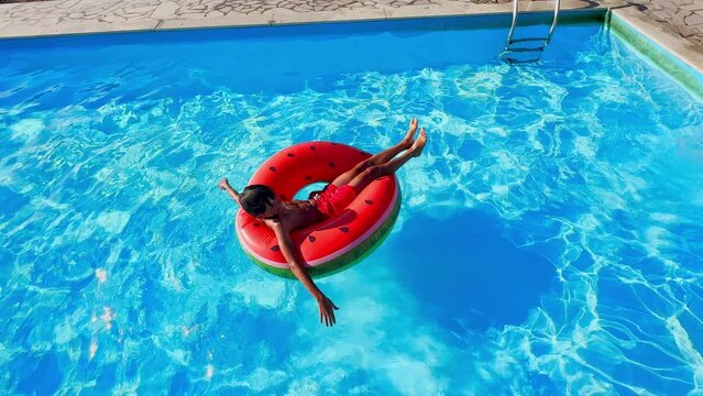Teen boy enjoys pool time on watermelon float view from above