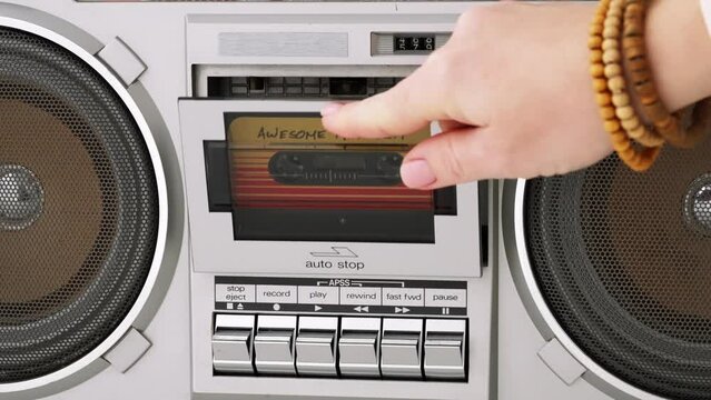 Woman hand puts cassette into deck recorder playing music close up. Analog tape recorder plays  audio cassette spins plays music close up slide top front. Retro tape reels rotate 