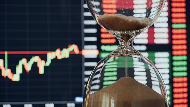 Time concept hourglass  pouring gold sand on background rising charts of cryptocurrency on financial exchanges on monitor. Eth and btc quotes on stock exchange. Time is money.