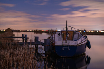 A boat anchored among the reeds at the edge of the river. Night landscape in a rural environment...