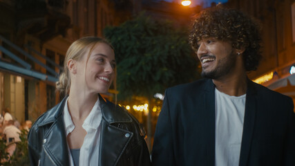 Two people walking city man woman happy couple stroll together smiling laugh positive friendship relationship harmony outside nighttime communication chat talk weekend enjoy reunion funny high five 