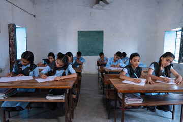 Group of indian village students in school uniform sitting in classroom doing homework, studying....