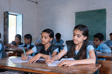 Group of indian village students in school uniform sitting in classroom doing homework, studying. Education concept