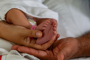 New born baby feet on the hands of a happy dad 