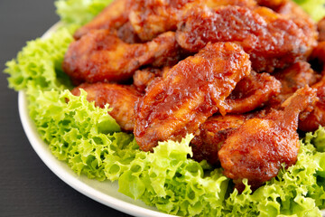 Homemade Honey BBQ Chicken Wings on a Plate on a black background, side view. Close-up.