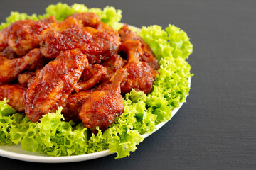 Homemade Honey BBQ Chicken Wings on a Plate on a black background, side view. Copy space.