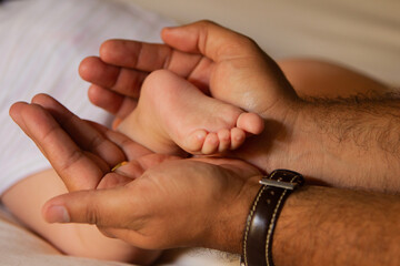 New born baby feet on the hands of a happy dad 