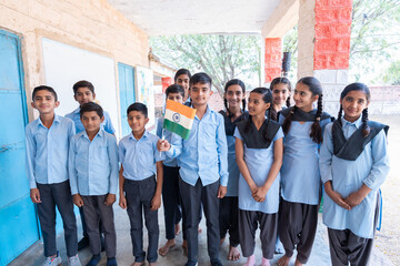 Group of happy village children in school uniform celebrating independence day with Indian flag in...