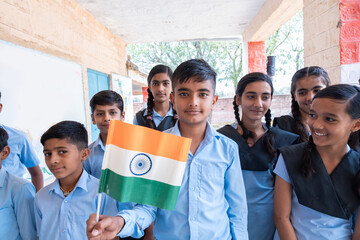 Group of happy village children in school uniform celebrating independence day with Indian flag in hand - concept of independence, republic day, patriotism and freedom. - obrazy, fototapety, plakaty