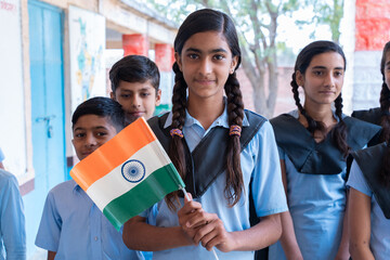 Group of happy village children in school uniform celebrating independence day with Indian flag in hand - concept of independence, republic day, patriotism and freedom. - obrazy, fototapety, plakaty