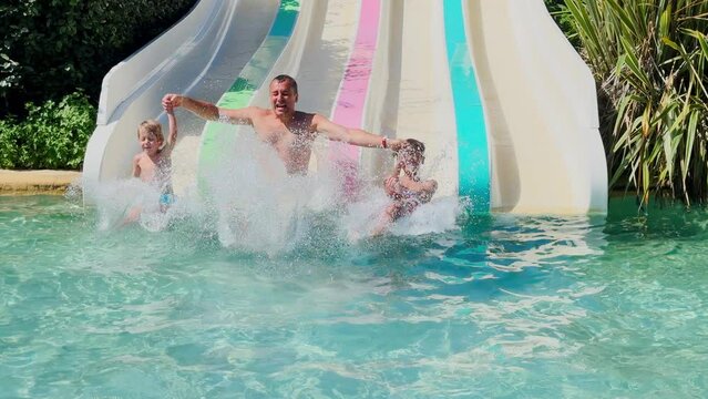Excited waterpark visitors, dad with kids riding a water slide