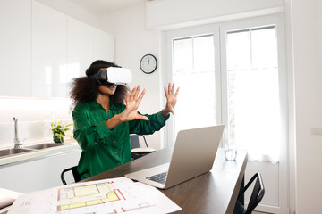 A black afro woman architect is working at home discussing her  virtual reality home project with...